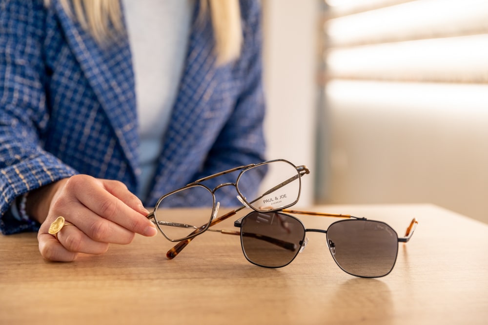 Une opticienne tiens la branche d'une lunette sur son bureau