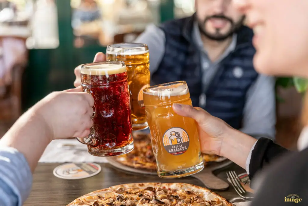 Photographe entreprise Clermont-Ferrand : Trois personnes tenant des verres de bière pour trinquer - Mise en scène de produits artisanaux – photographie de produits en Auvergne